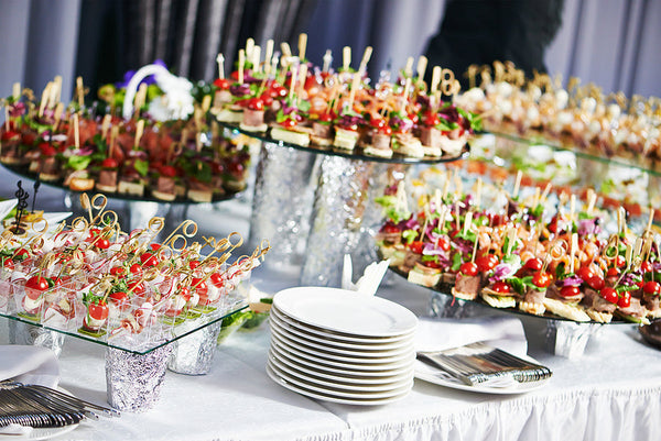 Elegant catering display with assorted bite-sized appetizers arranged on glass platters at a formal event
