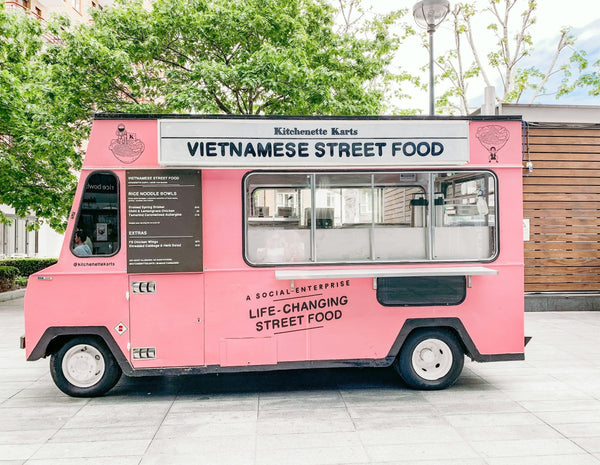 A pink Vietnamese street food truck parked outdoors, representing a modern entrepreneurial venture.
