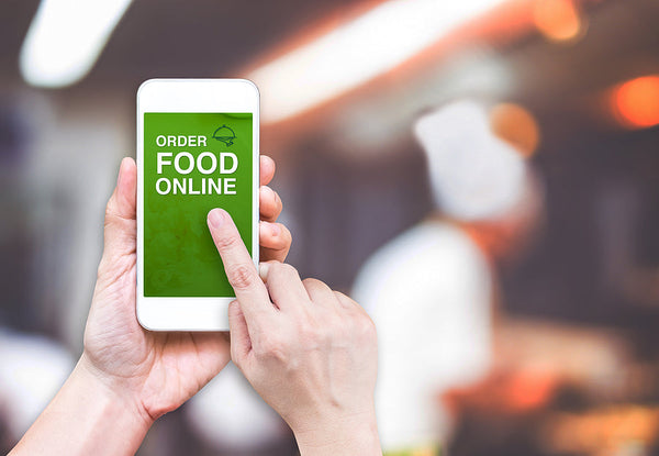 A woman holding a clipboard and checking inventory on grocery store shelves — representing preparation and organization in an online food business.