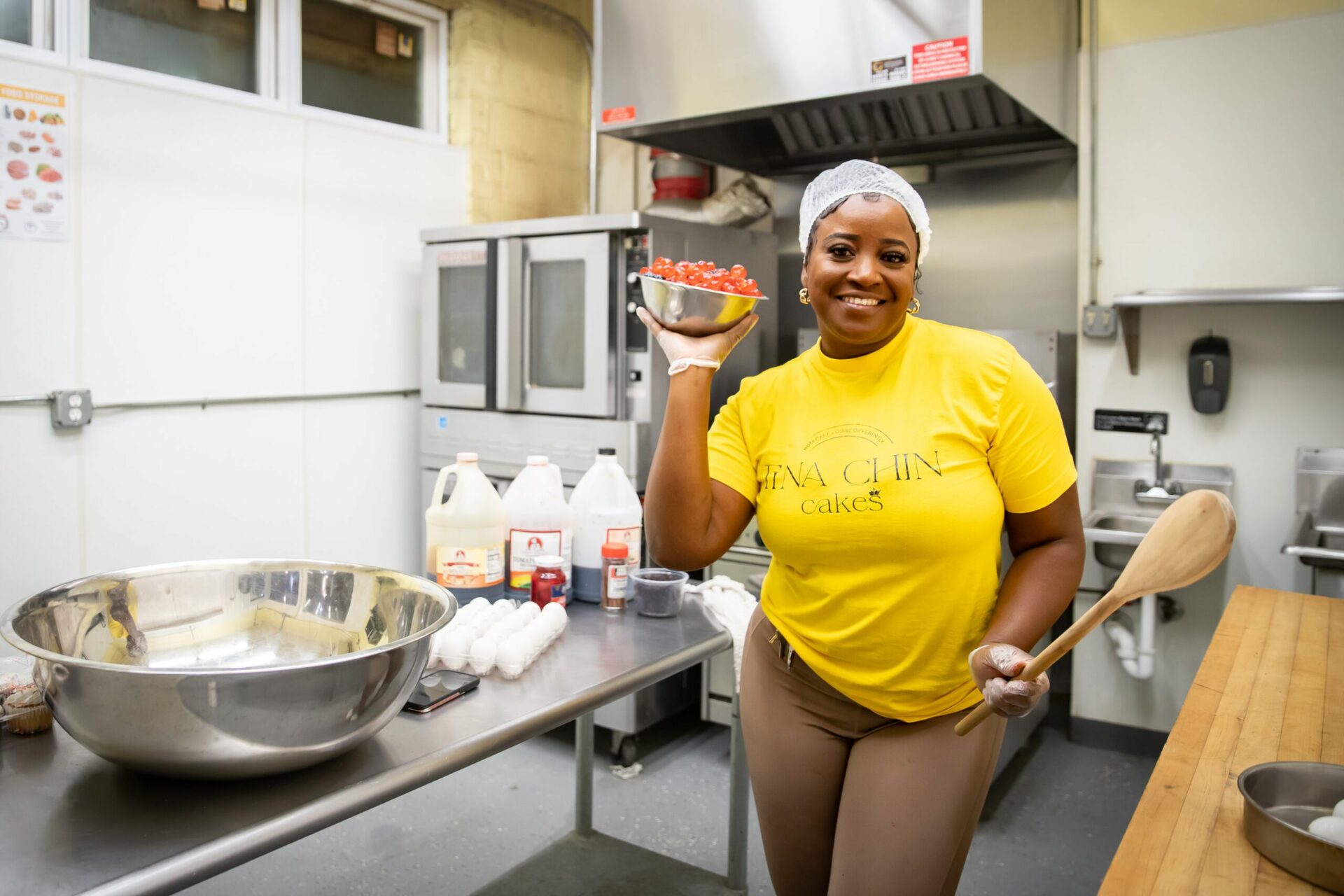 Smiling chef holding a bowl of cherries inside a commercial kitchen, used in FAQ section